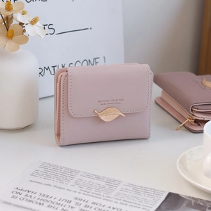 Detailed close-up of pink faux leather wallet with gold leaf buckle and fine stitching