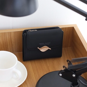Close-up of black PU leather wallet featuring a gold leaf buckle on a wooden tray