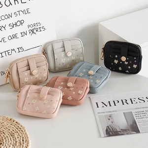 Flat lay of multiple floral mini wallets in pastel colors with gold zipper details