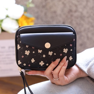 Detailed view of black floral passport wallet featuring a metal buckle and wrist strap