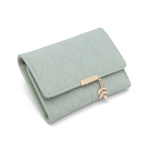 Détail du portefeuille en cuir vert menthe avec coutures matelassées et pendentif feuille