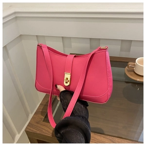Detail of rose red underarm bag with gold twist lock and sleek curved PU leather finish