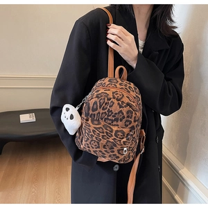 Close-up of leopard print mini backpack featuring a plush bear charm and brown straps
