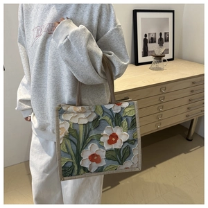 Detail view of 3D embossed floral patterns on a large linen tote bag in a home setting