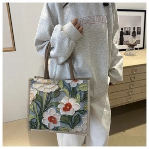 Detail of 3D floral embroidery and brown fabric strap on a large linen tote bag