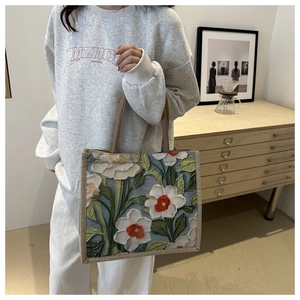 Detail of floral embroidery on linen tote bag with textured oil painting style