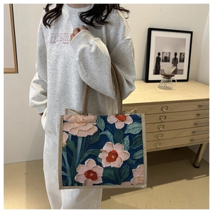 Detail of retro linen tote bag with textured pink floral embroidery and woven handles