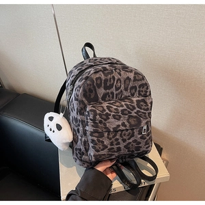Detail of leopard print mini backpack with white panda plush pendant and black zippers