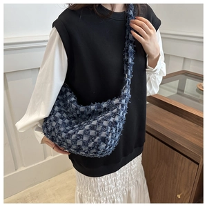 Dettaglio della borsa tote in denim a scacchi blu e bianchi con bordi sfilacciati