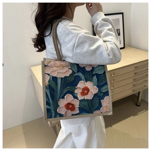 Close-up of floral embroidery on a large navy linen tote bag with sturdy brown straps