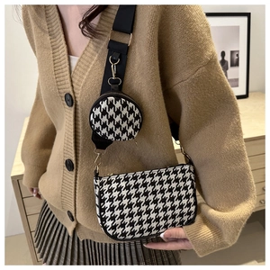 Detail of houndstooth crossbody bag with mini pouch and gold hardware on model