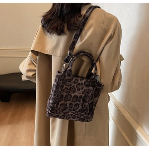 Détail d'un sac cabas léopard avec bandoulière réglable sur un trench-coat beige élégant