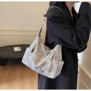 Détail de la texture vieillie et poches zippées fonctionnelles sur un cabas gris