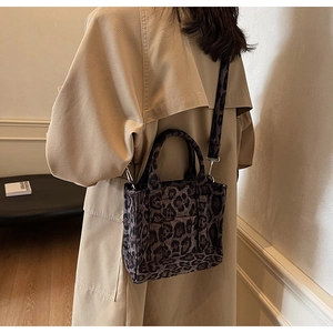 Vue arrière d'un sac cabas en toile à imprimé léopard porté avec un trench kaki