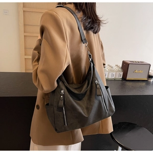 Detail of dark grey suede hobo bag with adjustable strap and vertical zipper pockets