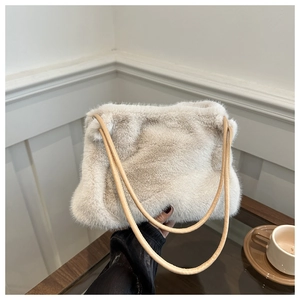 Detailed close-up of a beige plush shoulder bag with dual slim leather straps and soft fur