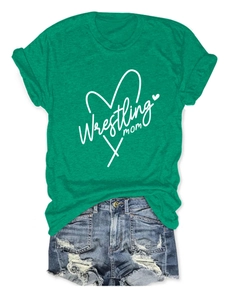 Flat lay detail of grass green Wrestling Mom T-shirt with heart and distressed denim shorts