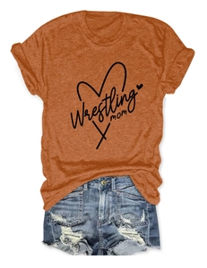 Detail of orange wrestling mom t-shirt with heart graphic and distressed denim shorts