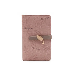 Détail du portefeuille en cuir rose avec imprimé feuilles et pendentif doré