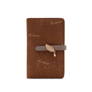Détail du portefeuille en similicuir marron avec motif feuille et pendentif doré