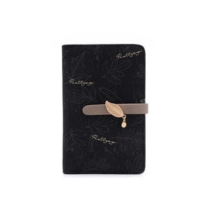 Détail du portefeuille noir mat avec motif de feuilles et pendentif en métal doré