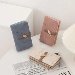 Détail de trois portefeuilles minimalistes avec motifs de feuilles et pendentifs en métal