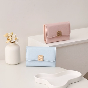 Close-up of pink and blue faux leather wallets with gold buckles on geometric stands