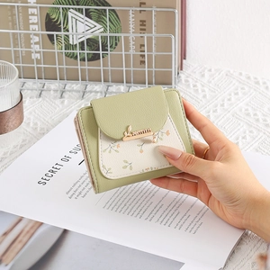 Close-up of small floral PU leather wallet with metal leaf pendant and snap closure