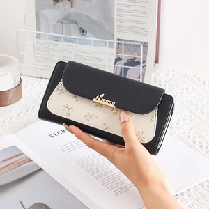 Close-up of floral patchwork wallet with elegant golden leaf buckle and zipper detail