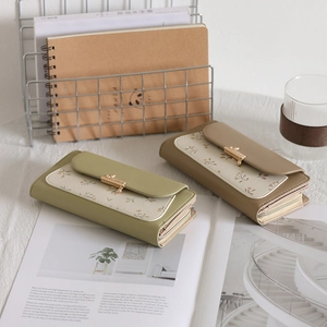 Detailed side view of floral print wallets in green and khaki with golden clasps