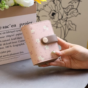 Nahaufnahme einer rosa geblümten PU-Ledergeldbörse mit Druckknopf und Reißverschluss