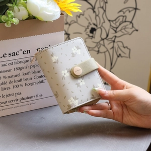 Nahaufnahme der floralen PU-Ledergeldbörse mit grünem Druckknopf in der Damenhand