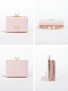 Detail of light pink tri-fold wallet featuring pearl kiss-lock and gold bow ornament