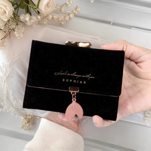 Nahaufnahme der schwarzen Geldbörse mit goldener Schrift und einem rosa Blattanhänger