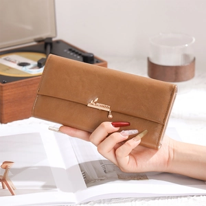 Close-up of brown long leather wallet with elegant gold leaf pendant and logo detail