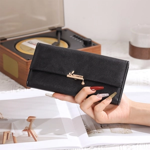 Close-up of black leather long wallet featuring golden leaf charm and textured surface