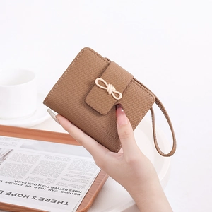 Brown lychee texture short wallet featuring a cream bow buckle and leather wrist strap