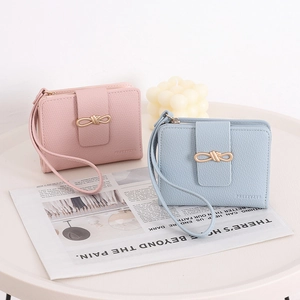 Close-up of pink and blue pebble leather wallets with gold knot buckles on a table