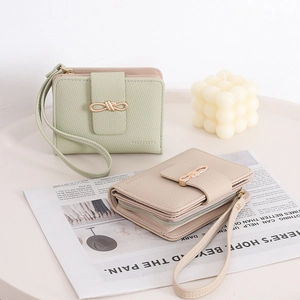 Short leather wallets in light green and beige with gold buckle and wristlet straps