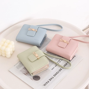 Short leather wallets for women with golden bow buckle and wrist strap in pastel colors