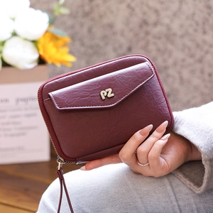 Detail of burgundy leather wallet with zip closure, metal PZ logo, and wrist strap handle