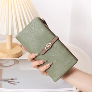 Détail du portefeuille vert olive avec motifs de feuilles gaufrés et boucle dorée élégante