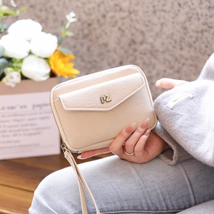 Detail of beige leather passport wallet with metal PZ logo and wrist strap in hand