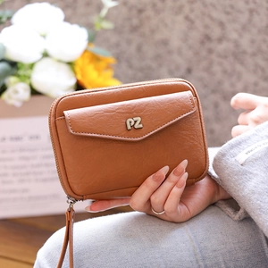Close-up of brown textured leather passport wallet with metal logo and V-flap pocket