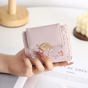 Pale pink bi-fold wallet featuring printed cherry patterns and a gold leaf metal clasp