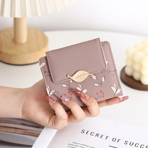 Close-up of pink PU leather wallet with metallic leaf clasp and floral patterns