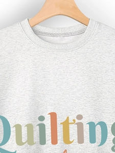 Detail of grey heather sweatshirt with colorful quilting typography and crewneck collar
