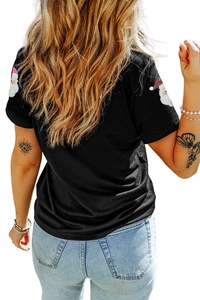 Détail de l'imprimé Père Noël sur la manche d'un t-shirt noir à paillettes pour femmes