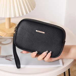 Close-up of black pebbled leather wristlet clutch with double zippers and gold logo