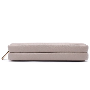 Detail view of double gold zippers on a taupe pebbled leather multifunctional passport bag